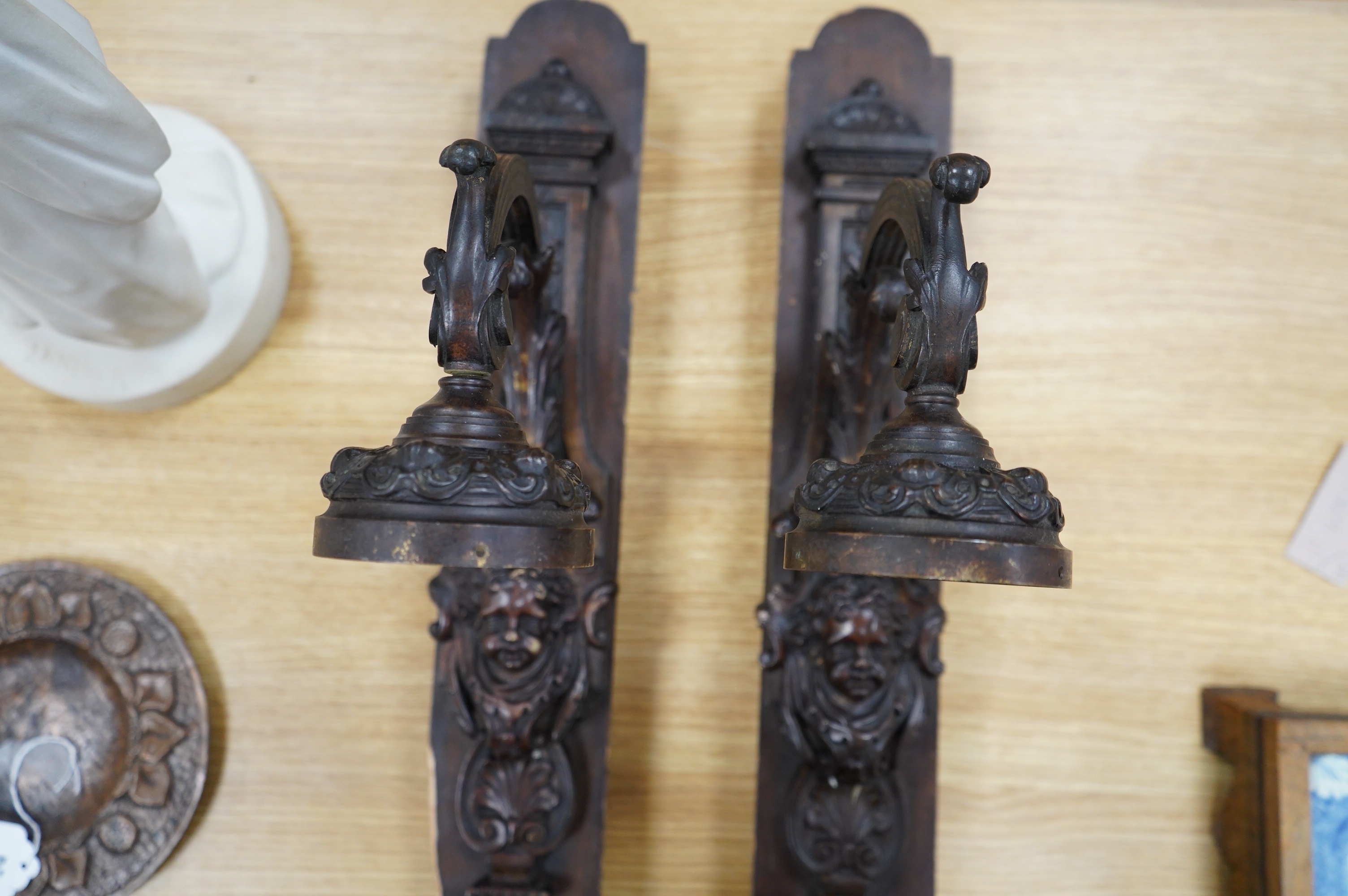 A pair of French bronze wall lights, c.1900 decorated with masks, mounted on wooden plinths, 54cm high. Condition - poor to fair